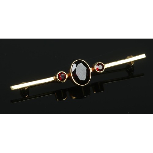 343 - A 9ct gold three stone garnet bar brooch. 2.02g.