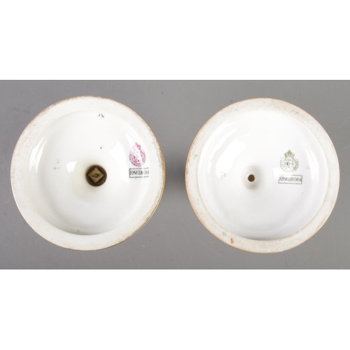 414 - Two Royal Worcester blushware candlesticks on circular bases, decorated with flowers. Dated 1900 and... 