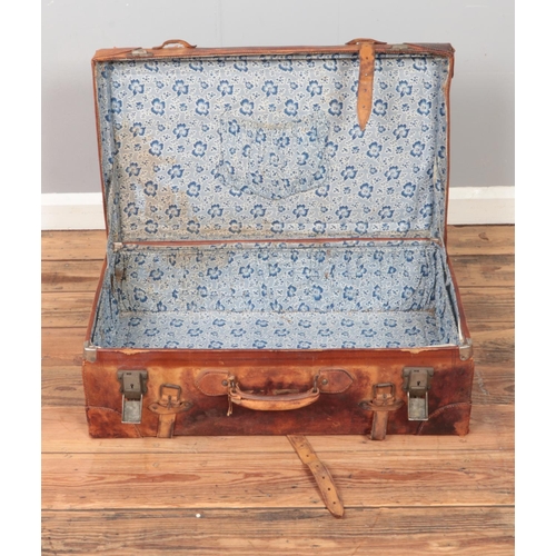 264 - A large vintage leather suitcase with floral fabric lining.