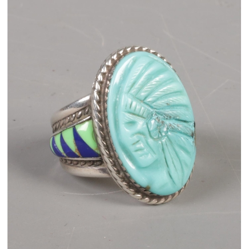 382 - A silver Navajo style ring with carved portrait of a Native American and enamel shoulders. Size T. 1... 