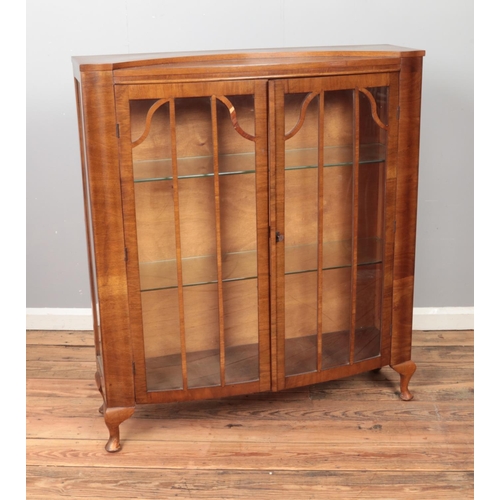 445 - A walnut and glass display cabinet featuring two glass shelves and double doors. Approx. dimensions ... 