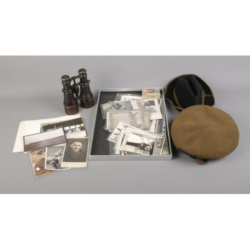 110 - A collection of military items including photographs, caps and Colmont Paris binoculars.