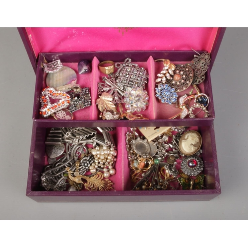 12 - A cantilever jewellery box with contents of costume jewellery. Includes brooches, rings and dress cl... 