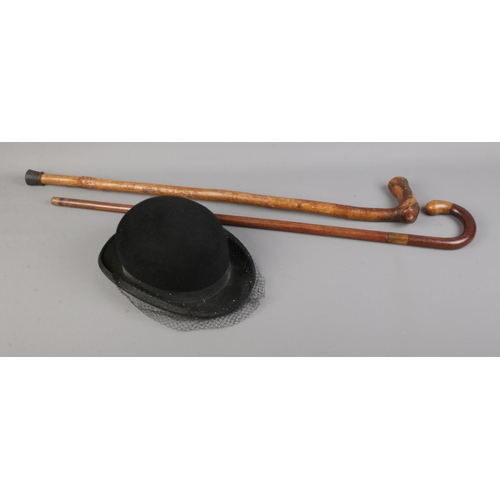 136 - A Herbert Johnson bowler hat with fascinator along with two carved walking sticks.