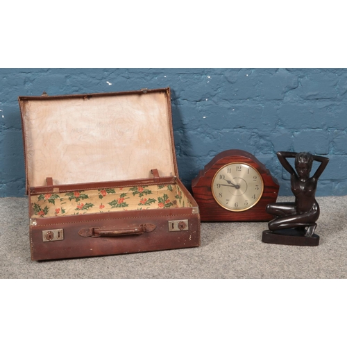 223 - A small leather suitcase along with mantle clock and figure of posed naked woman.