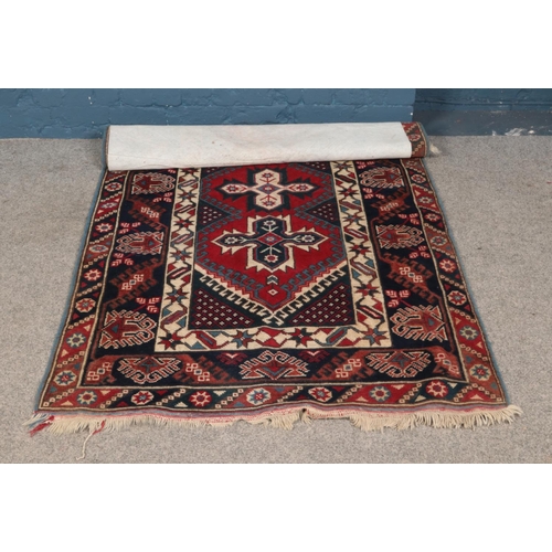 278 - A ground wool rug featuring geometric design and fringed edging.