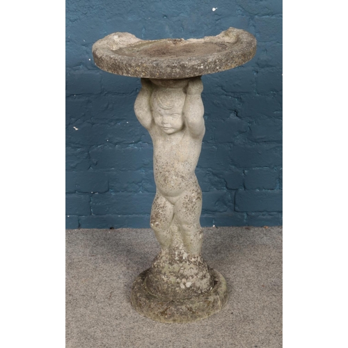 327 - A concrete bird bath formed as a child raising dish. Approx. dimensions 41cm x 76cm.