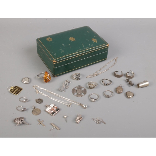 431 - A small green box containing various oddments of silver jewellery. To include charms, rings, brooche... 