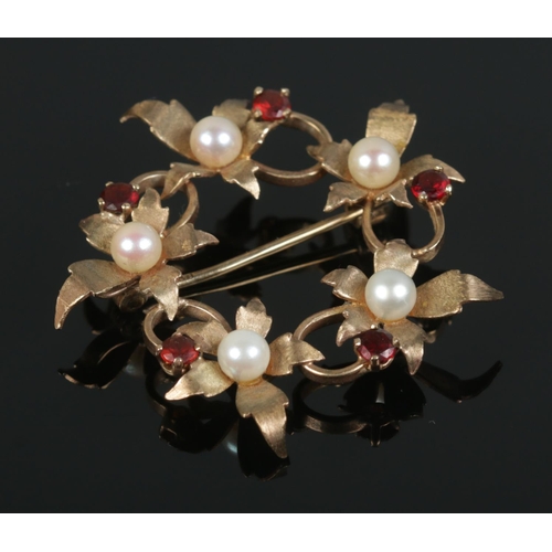 436 - A 9ct Gold Garnet and Pearl brooch in a circular leaf form. Total weight: 4.9g