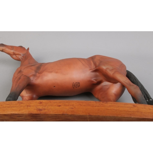 453 - A connoisseur model by Beswick of Red Rum, raised on wooden plinth. Height: 32cm.