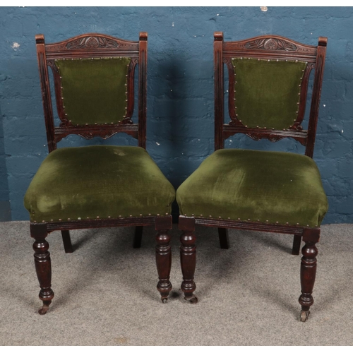 470 - A pair of Victorian upholstered dining chairs featuring carved back detail and turned supports.