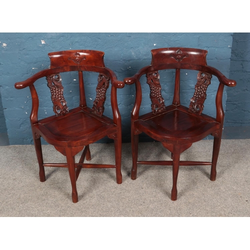 489 - A pair of carved mahogany bow armchairs featuring floral decoration.