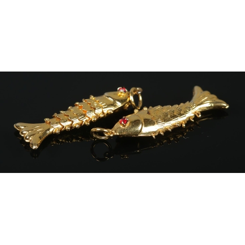 110 - Two yellow metal articulated fish pendants, both set with red coloured stone eyes. Length 3cm. 1.79g... 