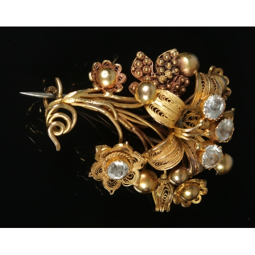 115 - An 18ct gold cannetille work flower brooch set with four paste stones. Maker's mark FM. 4.5cm x 3.5c... 