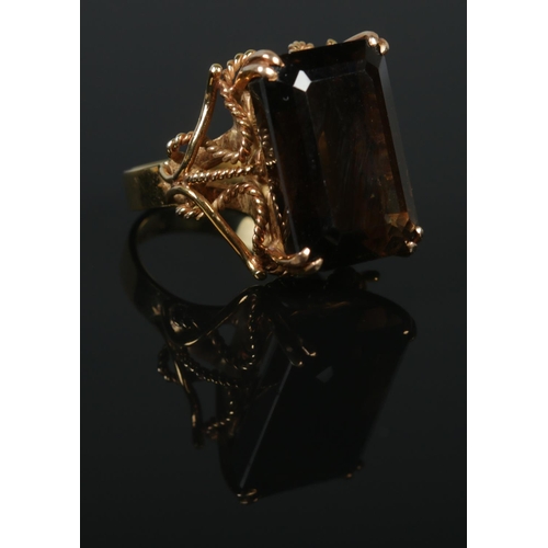 123 - A 14ct gold dress ring set with a large faceted smoky quartz stone. Having rope twist shoulder decor... 