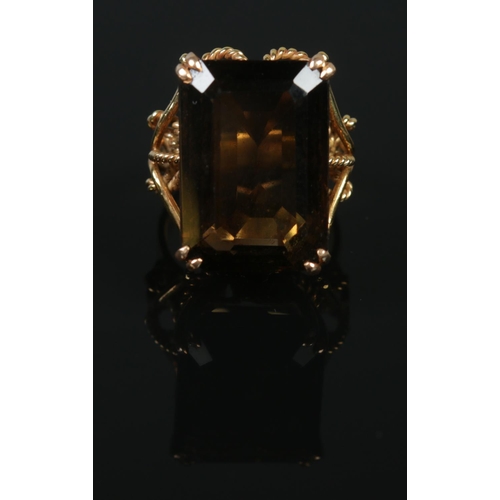 123 - A 14ct gold dress ring set with a large faceted smoky quartz stone. Having rope twist shoulder decor... 