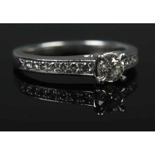 128 - A platinum and diamond ring. The central brilliant cut stone (approximately 0.3ct) flanked by seven ... 