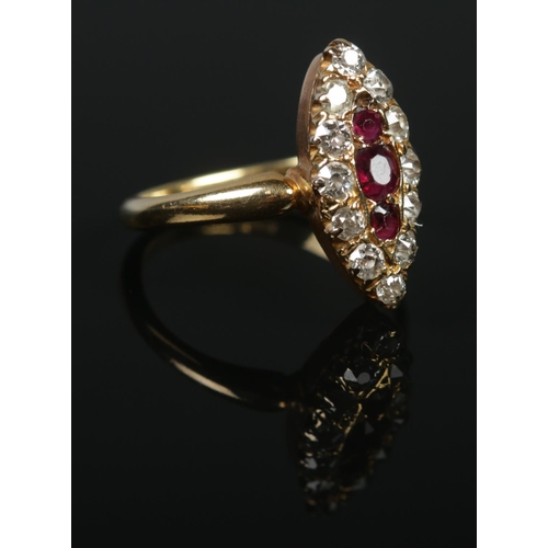 134 - An 18ct gold diamond and ruby navette ring. The three graduating ruby stones within a border of twel... 