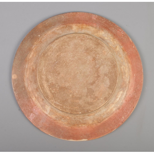 14 - An Islamic Samanid style earthenware dish with Kufic border and central motif. Diameter 32.5cm.