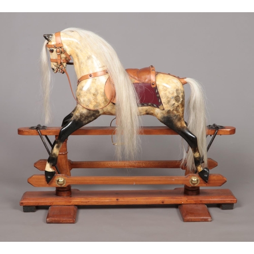 171 - A vintage child's painted wooden rocking horse raised on pine stand. Having glass inset eyes and lea... 