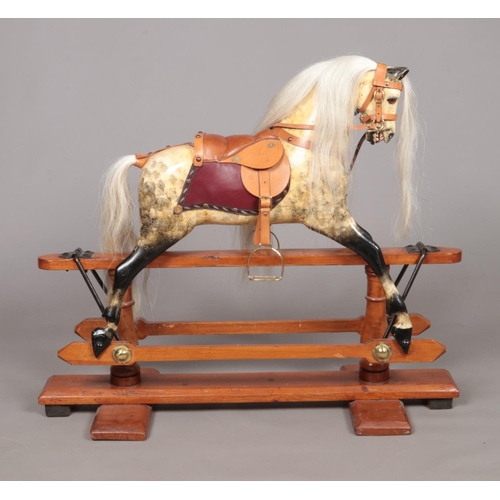 171 - A vintage child's painted wooden rocking horse raised on pine stand. Having glass inset eyes and lea... 