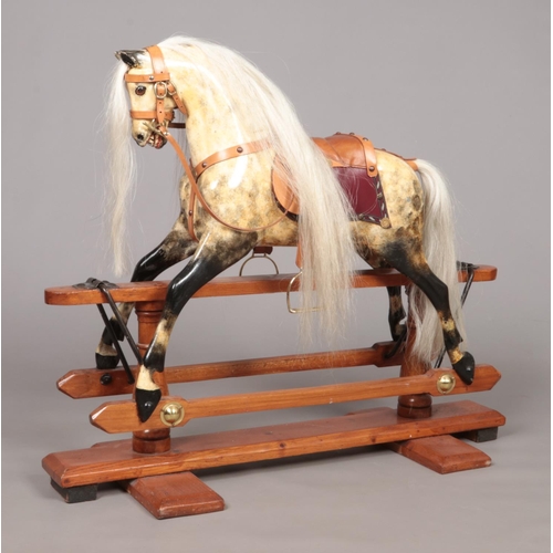 171 - A vintage child's painted wooden rocking horse raised on pine stand. Having glass inset eyes and lea... 