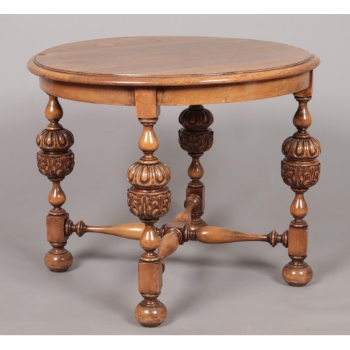 173 - An oak and mahogany circular occasional table with pineapple supports and turned stretcher. Height 5... 