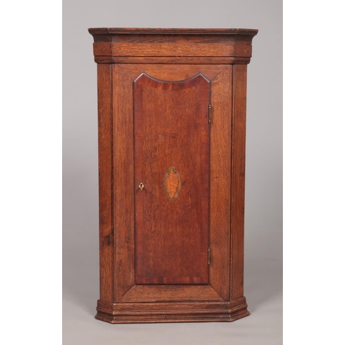 174 - A Georgian oak corner cupboard with shell patera inlaid door. Height 88.5cm, Depth from back corner ... 