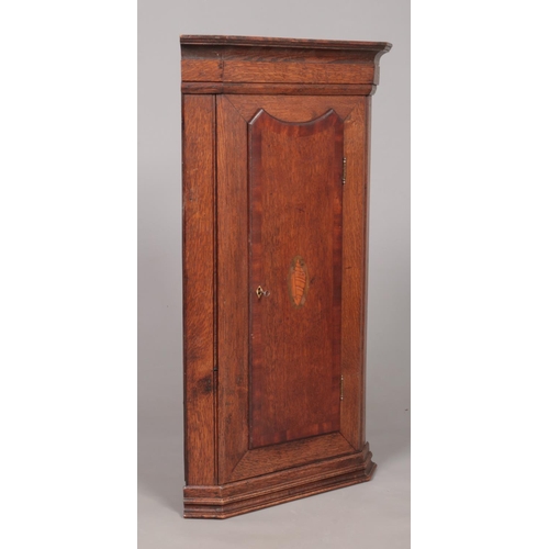 174 - A Georgian oak corner cupboard with shell patera inlaid door. Height 88.5cm, Depth from back corner ... 