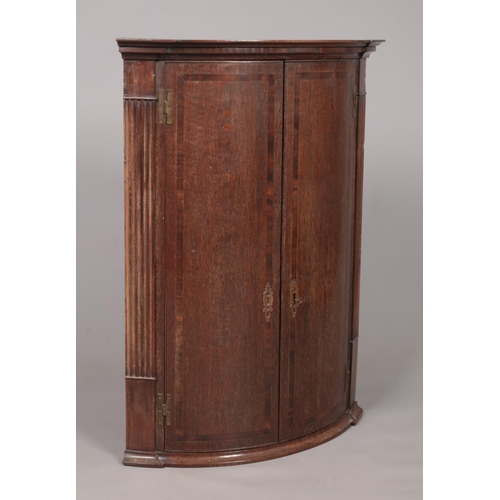 175 - A large Georgian oak bow front corner cupboard with crossbanded doors. With key. Height 96cm, Depth ... 