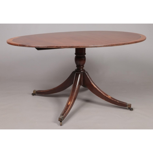 177 - A Regency mahogany tilt top dining table raised on centre pedestal with four splay supports. Label f... 