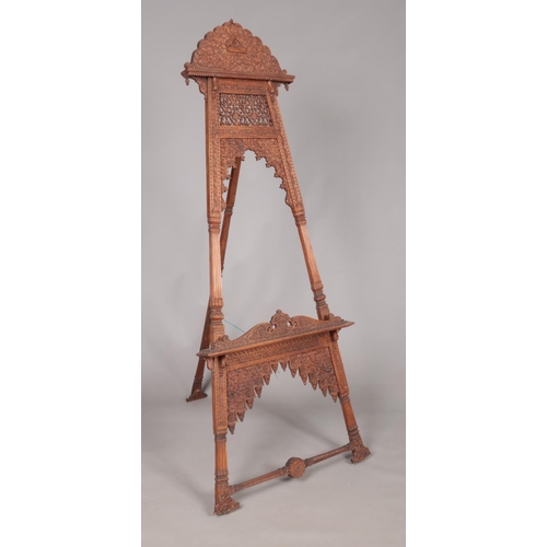 179 - A large easel with extensively carved floral decoration. Height 180cm.