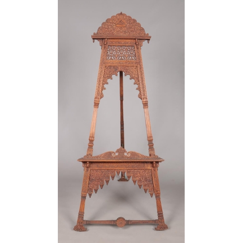 179 - A large easel with extensively carved floral decoration. Height 180cm.