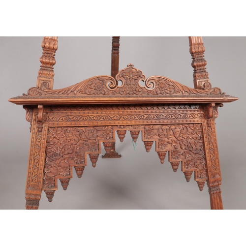 179 - A large easel with extensively carved floral decoration. Height 180cm.