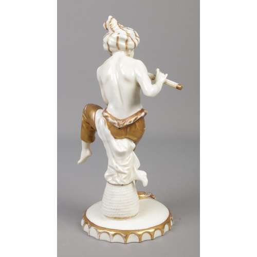 30 - A Sitzendorf porcelain figure of a snake charmer with gilt decoration. Height 22cm.