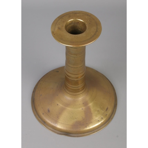 64 - A 17th century brass candlestick with trumpet base and bobbin stem. Height 19.5cm.