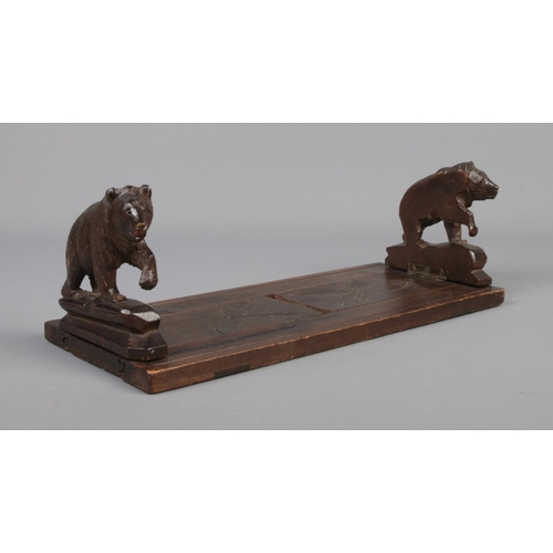 77 - A Black Forest wooden book stand with carved bears to each end.