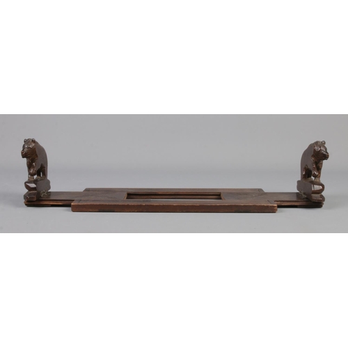 77 - A Black Forest wooden book stand with carved bears to each end.