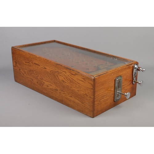 85 - An early 20th century bagatelle game, The Advance Pin Table. With oak case and glazed top, being coi... 