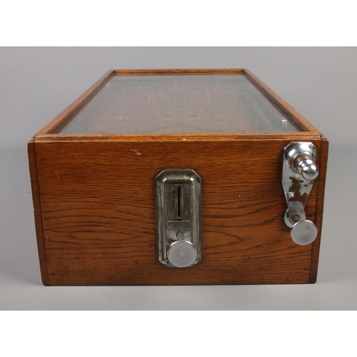 85 - An early 20th century bagatelle game, The Advance Pin Table. With oak case and glazed top, being coi... 