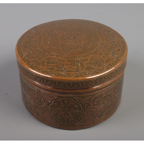 63 - An Eastern circular copper box with extensive engraved decoration. Height 7.5cm, Diameter 12cm.