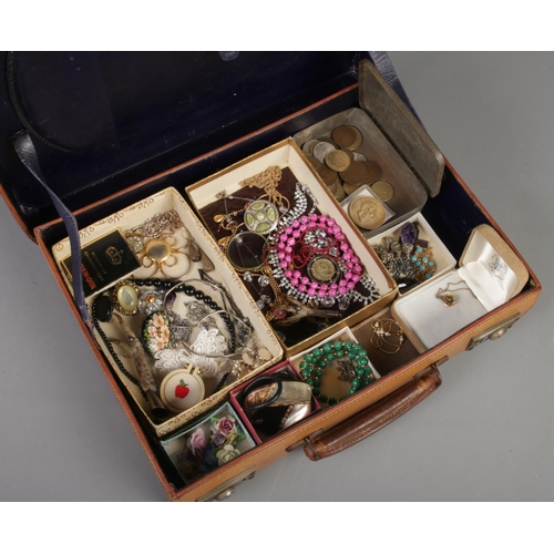 275 - A small leather case with contents of vintage costume jewellery and coins. Includes pheasant foot br... 