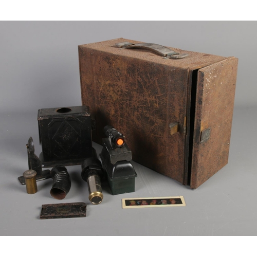 394 - A Houghton-Butcher magic lantern projector converted to electric with storage tin and assorted spare... 