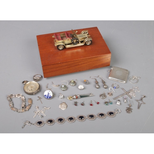 524 - A vintage cigarette box surmounted with a car having contents of mostly silver items and jewellery. ... 