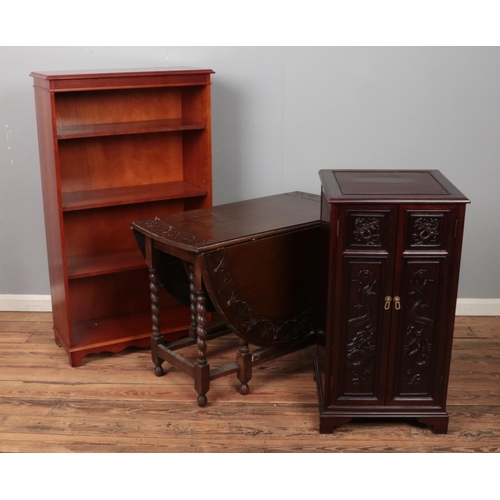 568 - Oak dropleaf table with barley twist legs along with Chinese hardwood cabinet and yew wood bookcase