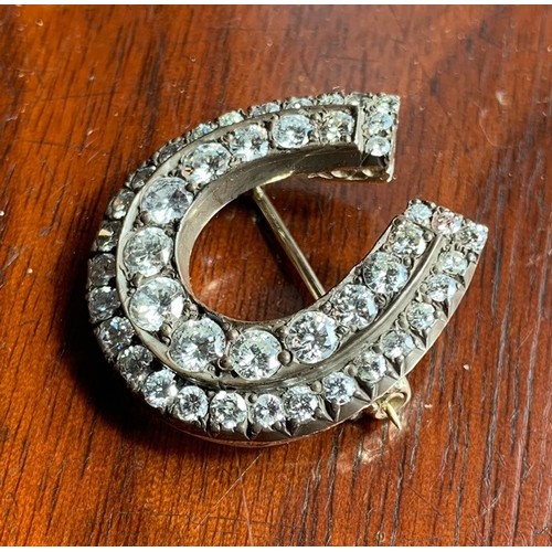 118 - A yellow metal and diamond horse shoe brooch. Set with 44 graduating brilliant cut stones (largest s... 