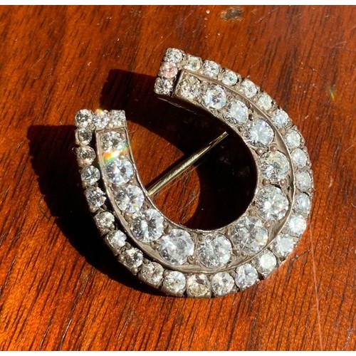 118 - A yellow metal and diamond horse shoe brooch. Set with 44 graduating brilliant cut stones (largest s... 