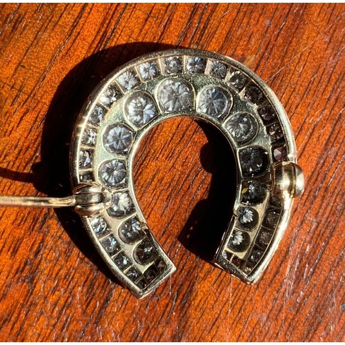 118 - A yellow metal and diamond horse shoe brooch. Set with 44 graduating brilliant cut stones (largest s... 