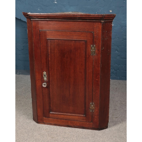 547 - A mahogany corner cupboard featuring decorative brass escutcheon. Approx. dimensions 83cm x 110cm x ... 