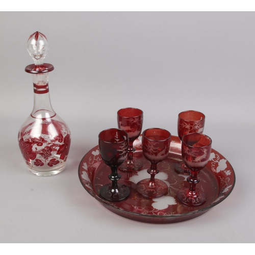 105 - A cranberry glass decanter and serving tray set along with five winter themed glasses.